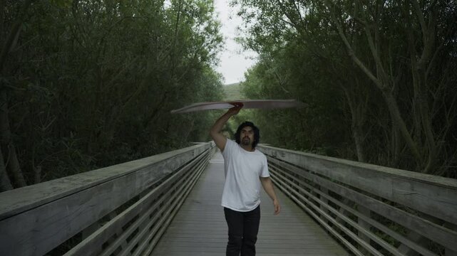 Man Releasing Painted Board Into Air And Catching It On Wooden Footbridge - Steady Cam