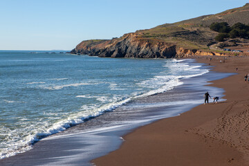 Obraz premium A father and child play on the sandy shore of Rodeo Beach, Marin Headlands, California, USA, enjoying a sunny day by the Pacific Ocean.