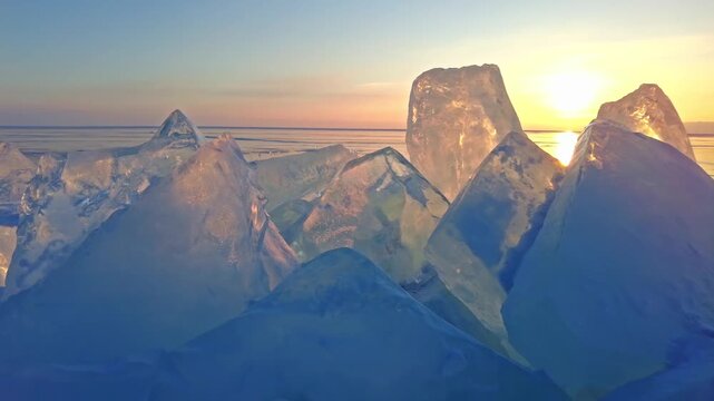Sunlight glowing behind sharp chunks of frozen lake ice at sunset hour.