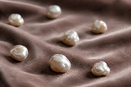 Irregular pearl nodules scattered on velvet fabric in close-up with soft texture and shallow depth.