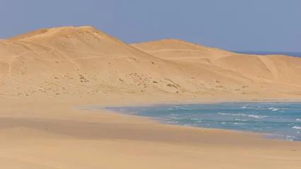 A minimalist perspective on the vast Viana desert landscape in Boa Vista, Cape Verde. The scene is a striking abstract composition formed by the golden sand dunes. © kapros76