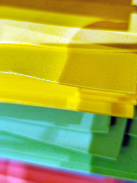 Stacks of colorful felt fabric sheets, paper in orange, red, green, brown, and blue on a metal shelf. Craft materials displayed in a store, ideal for art and DIY projects.
