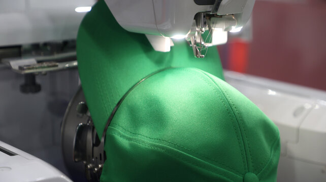 Automated embroidery machine stitching a green baseball cap with precision