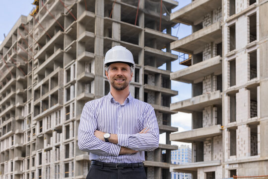 Young smiling man architect wearing a helmet looking to the side in building under construction
