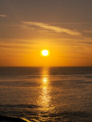 Fototapeta premium Close-up view of the setting sun above the ocean in Bali, Indonesia. Warm golden light fills the sky, creating a minimalist tropical sunset landscape.
