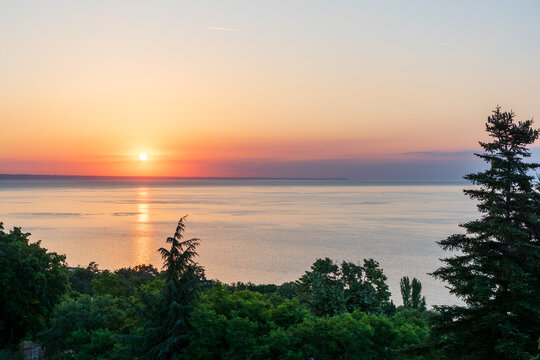 Golden Sunrise Reflection Across the Sea with Forest Foreground