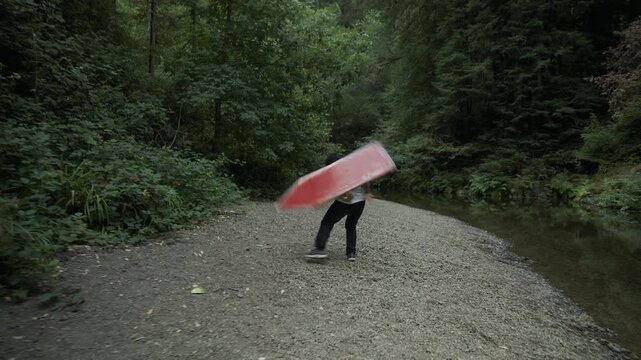 Happy Man Tossing And Spinning Painted Board on Gravel Path by Forest Stream - Wide, Steady Cam Shot