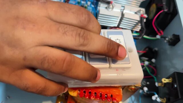 Technician Pressing Switch on Custom Inverter Circuit with Copper Transformer