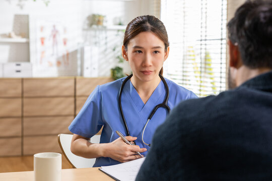 Doctor patient consultation clinic healthcare medical stethoscope woman asian uniform, Asian woman doctor blue uniform consults patient clinic office with stethoscope, clipboard, calm professional
