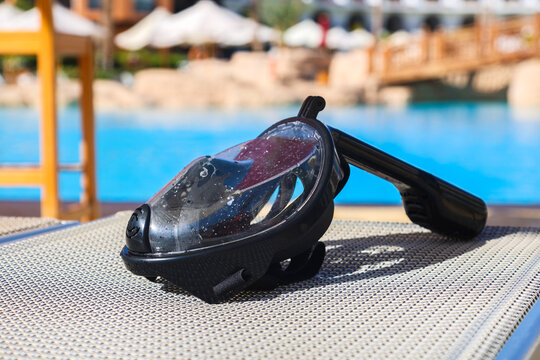 Snorkeling mask resting on the mesh of a sun lounger at a tropical beach resort.