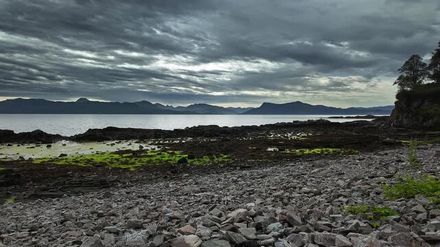 Motionlapse pan across the rocky Sound of Sleat shoreline at Armadale, Scotland, with dramatic clouds, calm sea, and distant mountains.