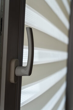 Modern door handle on a window showcasing layered white roller blinds, creating a contemporary interior design aesthetic suitable for home decor.
