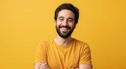 Fototapeta premium Confident Young Bearded Man Smiling with Arms Crossed Against Vibrant Yellow Studio Background