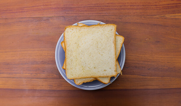 Fresh sliced ​​bread arranged on a plate with one slice leaning against the stack over a rustic wooden table. top view copy space.