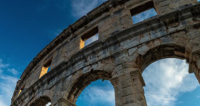 Time lapse of rushing clouds over the ancient Roman Pula Arena amphitheater walls with moving shadows in Croatia at sunny daylight