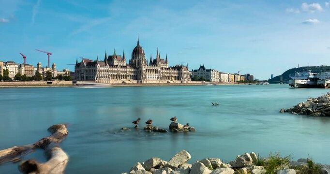 Budapest parliament building timelapse with rushing clouds over Danube river during bright sunny day and moving shadows on architecture