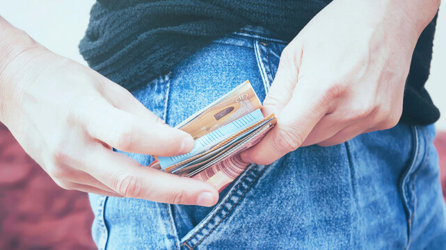 A man takes out euro banknotes from the pocket of his jeans, toned.