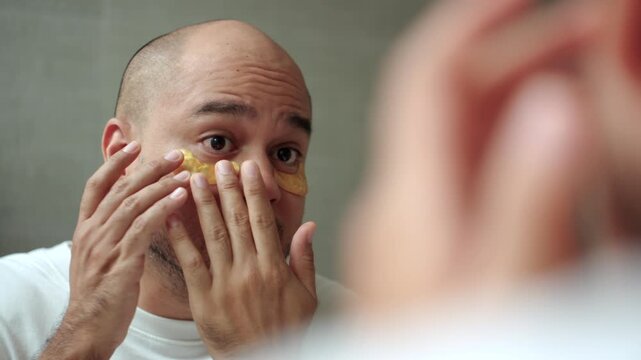 Man applying a sheet mask in front of a bathroom mirror during his morning skincare routine. Healthy aging longevity. Men self-care anti-aging skincare. wellness and preventive health concept.
