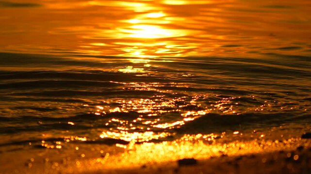 Sunset waves water reflection glistening on beach surface at golden hour creating peaceful nature background for travel and wellness meditation themes