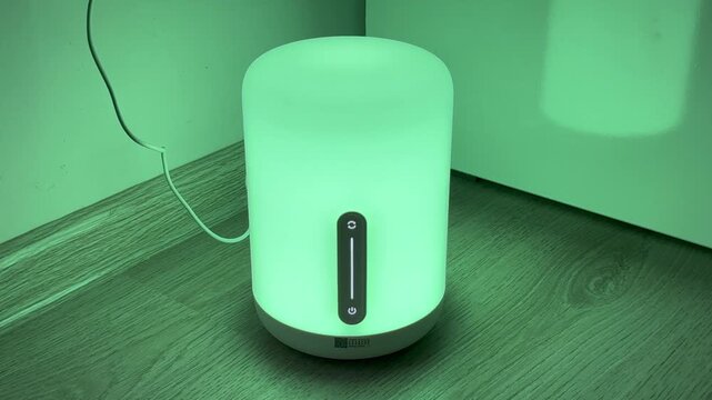 Xiaomi Mi Bedside Lamp 2 glowing with a soft ambient light on a wooden floor in a room corner