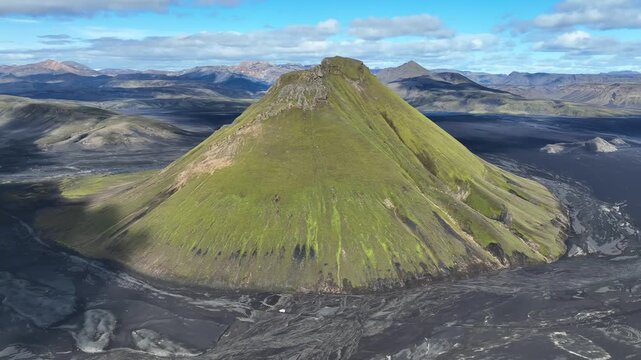 Aerial view of the iconic green Maelifell volcano rising from the black volcanic sands in the highlands of Kirkjubaejarklaustur, Skaftarhreppur, Iceland.