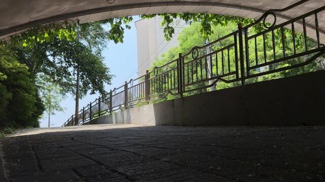 Walking view out of a concrete bridge underpass towards a peaceful suburban neighborhood street