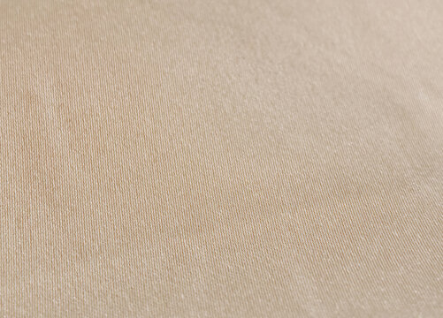 A high-resolution macro background showing the fine weave texture of natural satin cloth textile in a muted tan khaki color palette