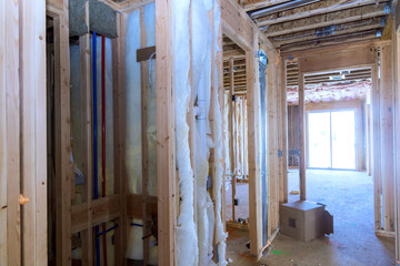 House under construction with wooden frames insulation materials being installed in interior space
