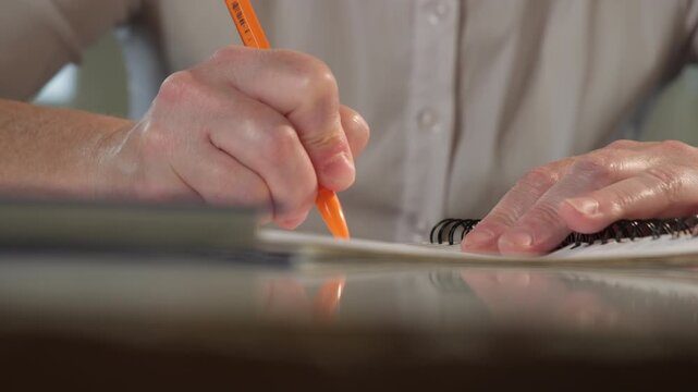 Female student's hand writes term paper during test or exam while sitting at desk close-up