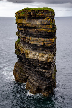 Majestic layered Dun Briste sea stack in the ocean under a dramatic stormy sky, coastal landscape of Ireland