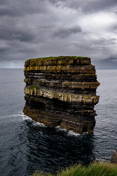Majestic layered Dun Briste sea stack in the ocean under a dramatic stormy sky, coastal landscape of Ireland