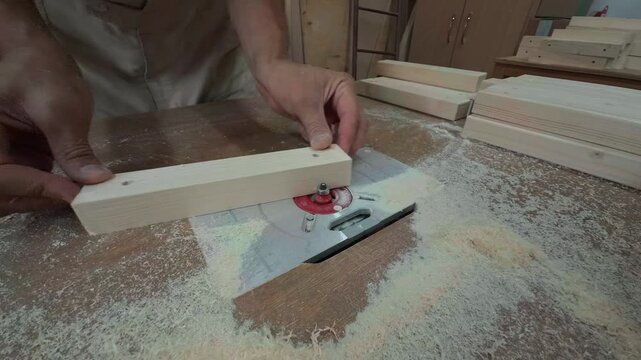 Authentic High Angle Close Up Of Unrecognizable Male Carpenter Hands Lifting Freshly Routed Wooden Block Off Red Metal Machine Plate On Dusty Workbench Inside Local Rustic Joinery Studio