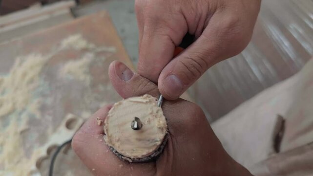 Unrecognizable self employed entrepreneur hands using screwdriver to extract wooden circle plug from hole saw drill bit inside small home manufacturing workshop during authentic handheld close up