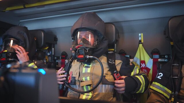Firefighters Donning Breathing Apparatus Inside Fire Engine