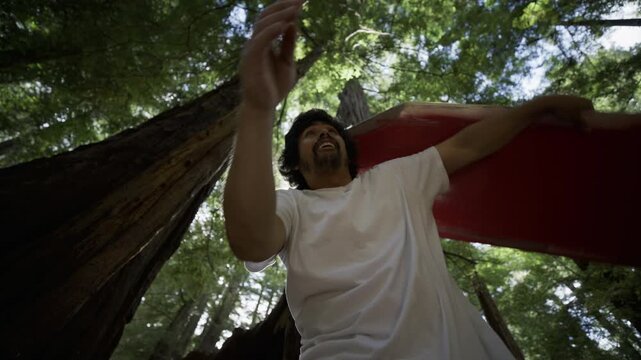 Man Waving Red Board Overhead Sunlight Lens Flare Redwood Canopy