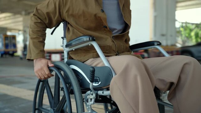 Happy disabled man using a wheelchair independently rolling down on accessible city sidewalk with barrier-free infrastructure. Equal access. Smart city, disability rights. Independent mobility.
