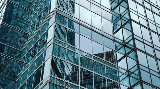 A sleek glass-and-metal facade of a multi-story building with a repeating geometric pattern in the background