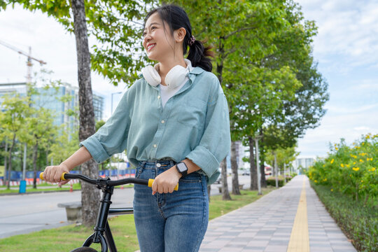 Asian woman riding a bicycle in a natural park.