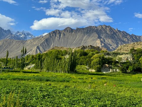Scenic Mountain Landscape Near Hopper Glacier with Green Fields and Blue Sky in Nagar Valley Gilgit Baltistan Pakistan