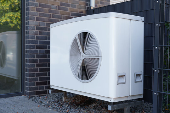 Modern outdoor air source heat pump installed beside a residential building exterior