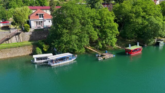 Drone view of tourist boats moored along the Drina River waterfront near Mehmed Pasha Sokolovic Bridge in Visegrad