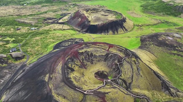 Aerial view of the dramatic Grabrok volcanic craters surrounded by lush green moss and dark volcanic soil with hiking trails in Bifrost, Borgarbyggd, Iceland.