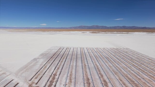 Drone aerial video of patterned salt fields and evaporation rows in Salinas Grandes, Argentina surrounded by mountains.