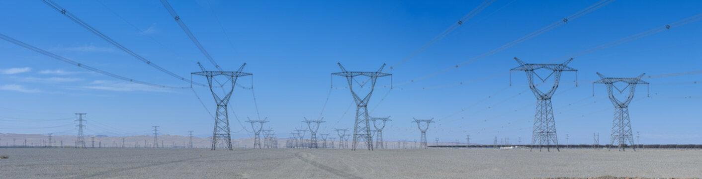 High-Voltage Transmission Towers Stretch Across the Gobi Desert Under a Clear Blue Sky
