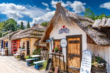 Row of thatched folk cottages with flowers and craft stalls under a blue sky, Bojnice © pszabo