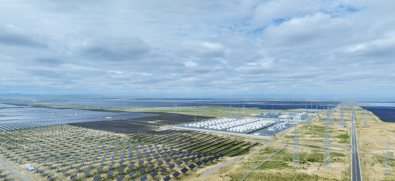 Aerial View of a Large Solar Farm with Co-Located Battery Storage and Substation Under Cloudy Sky
