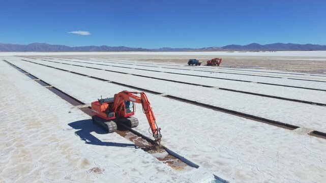 Drone aerial video of excavator, vehicles and salt evaporation rows in Salinas Grandes, Argentina.
