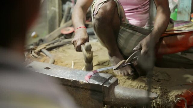 South Asian Blacksmith Hammering Glowing Hot Iron Blade on Anvil in Village Workshop