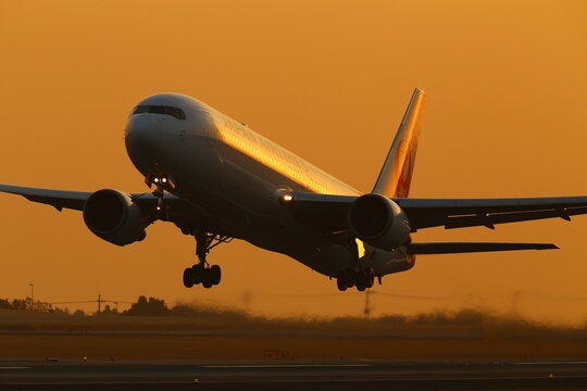 A Boeing 767 airliner taking off in golden evening light in Aso Kumamoto Airport, Japan.