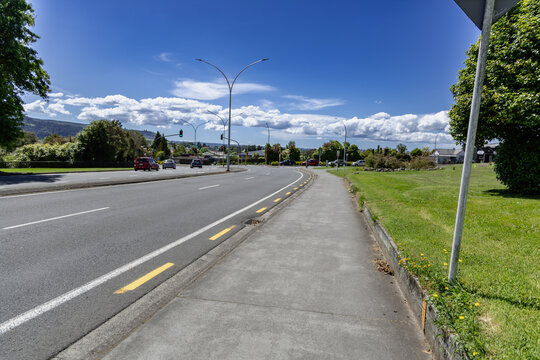 Sunny Urban Roadside Sidewalk Beside Green Park